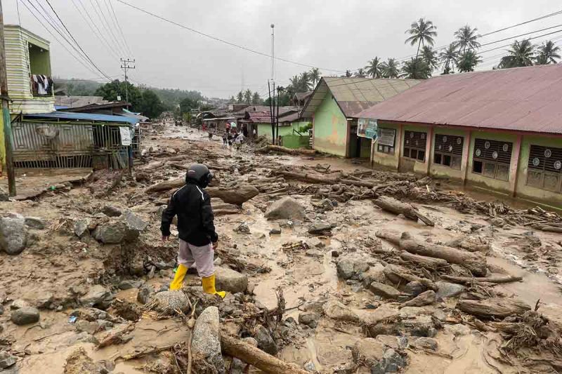 Warga berjalan di dekat bangunan sekolah yang terdampak banjir bandang di Ladang Rimba, Kabupaten Aceh Selatan. (Foto: Dok BPBD Kabupaten Aceh Selatan)
