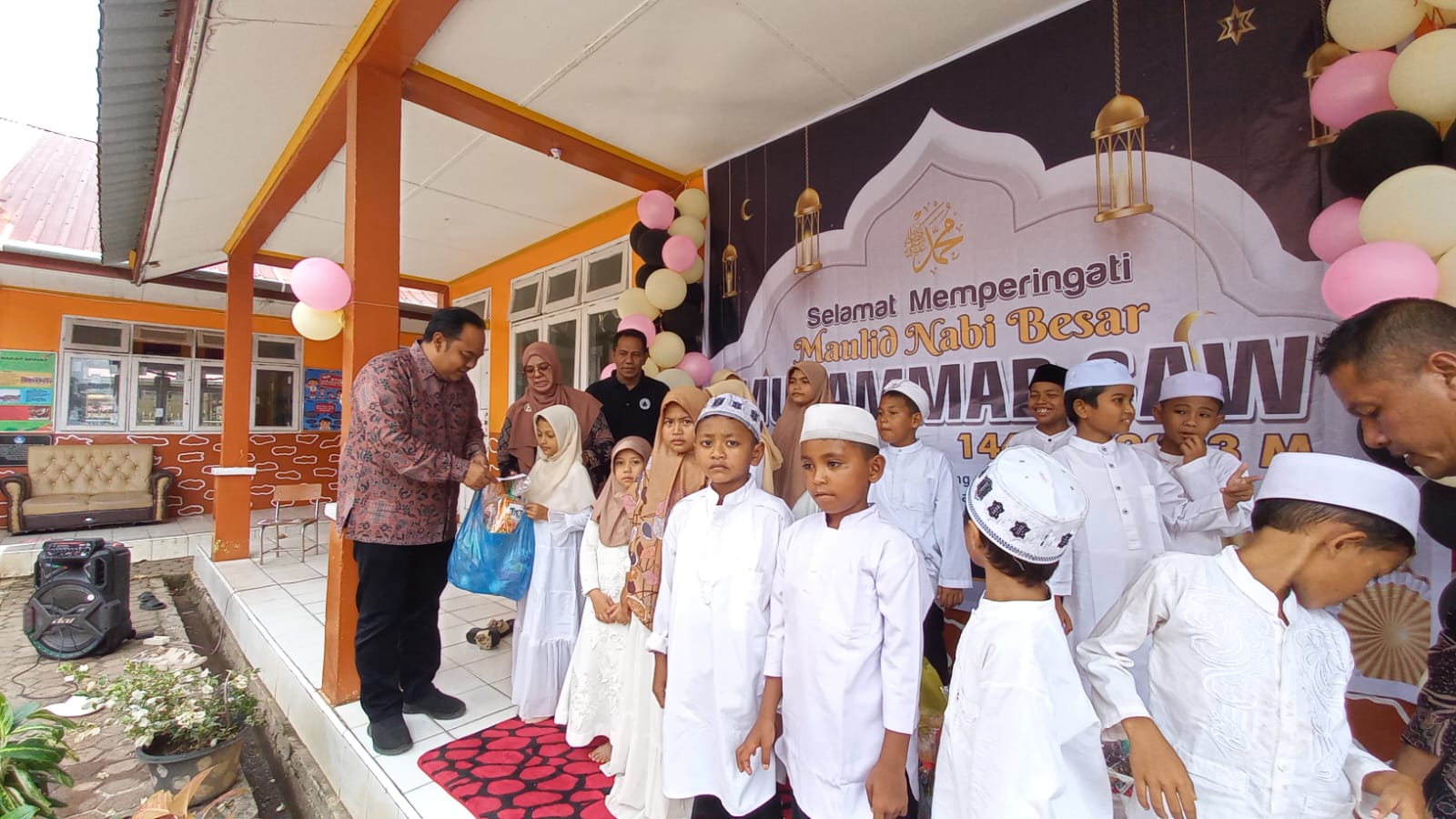 Sekda Aceh Jaya T Reza Fahlevi menyantuni anak yatim pada peringatan maulid akbar di SD N 2 Calang, Kamis (30/11/2023). (Foto: Dok. Humas Aceh Jaya)