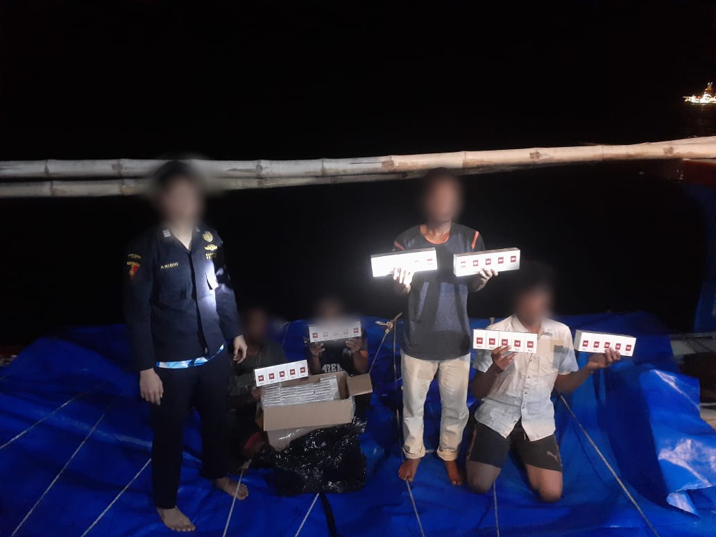 Pelaku penyelundupan memperlihatkan rokok ilegal usai ditangkap tim gabungan Bea Cukai di perairan Aceh. (Foto: Humas bea cukai Aceh)