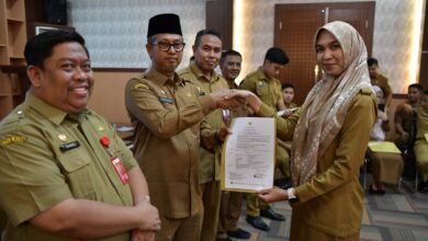 Asisten Administrasi Umum Sekda Aceh, Dr. Iskandar didampingi Kepala Badan Kepegawaian Aceh, Abdul Qohar dan Kepala Biro Organisasi Setda Aceh, Daniel Arca menyerahkan dokumen kepegawaian dalam rangka penepatan tugas lulusan IPDN Provinsi Aceh angkatan XXIX di Aula Badan Kepegawaian Aceh, Banda Aceh, Selasa, (19/12/2023). (Foto: Adpim Pemprov Aceh)