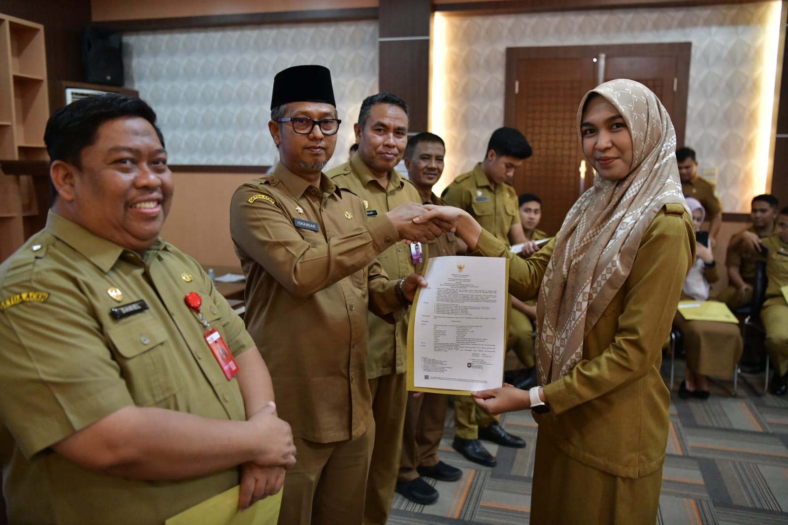 Asisten Administrasi Umum Sekda Aceh, Dr. Iskandar didampingi Kepala Badan Kepegawaian Aceh, Abdul Qohar dan Kepala Biro Organisasi Setda Aceh, Daniel Arca menyerahkan dokumen kepegawaian dalam rangka penepatan tugas lulusan IPDN Provinsi Aceh angkatan XXIX di Aula Badan Kepegawaian Aceh, Banda Aceh, Selasa, (19/12/2023). (Foto: Adpim Pemprov Aceh)
